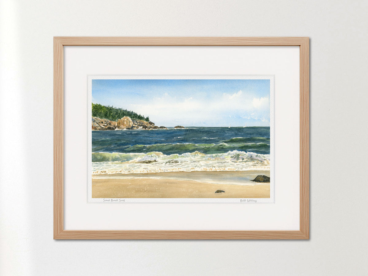 Framed watercolor print of Sand Beach Surf, Acadia National Park, Maine, in a warm wood frame on a neutral wall.