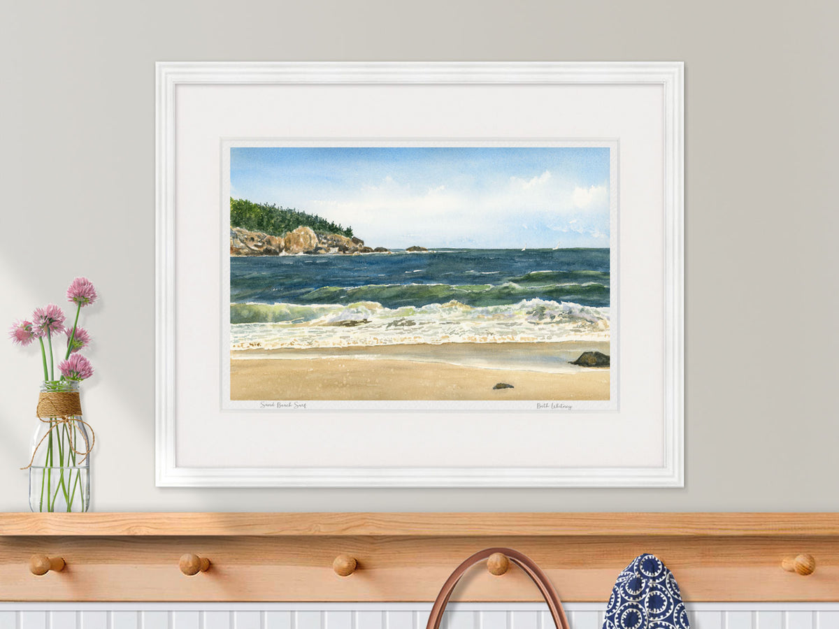 Framed watercolor print of Sand Beach Surf, Acadia National Park, in a white frame in a nautical entryway decor.