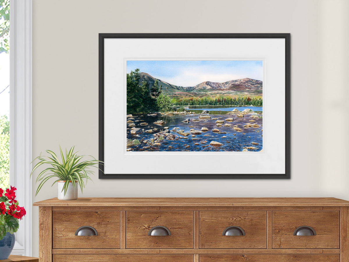 Framed original watercolor painting of Sandy Stream Pond, Baxter State Park, Maine, in a contemporary black frame on a rustic wood dresser.