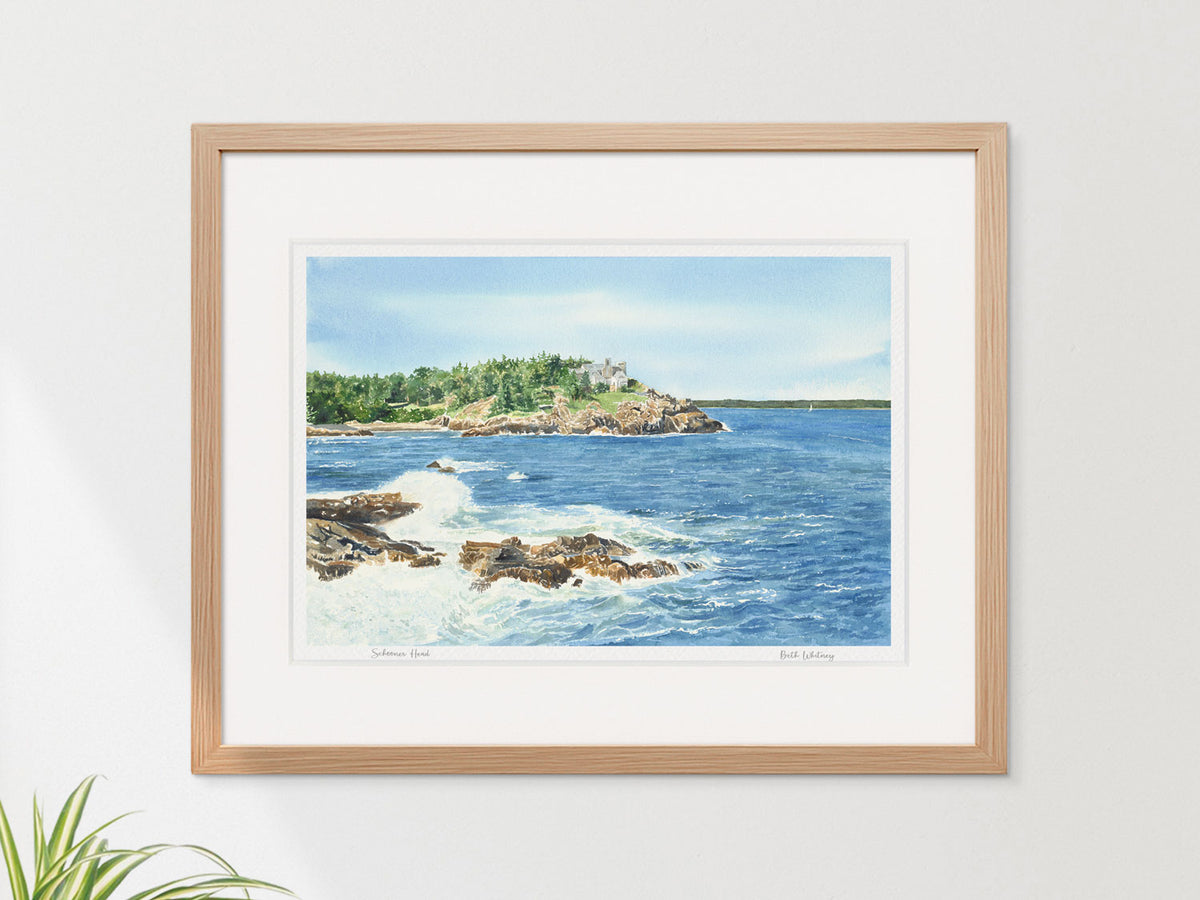 Framed watercolor print of Schooner Head, Acadia National Park, in a warm wood frame on a neutral wall.