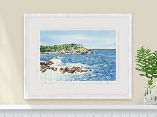Framed watercolor print of Schooner Head, Acadia National Park, in a white frame over a coastal inspired white shelf with fern.