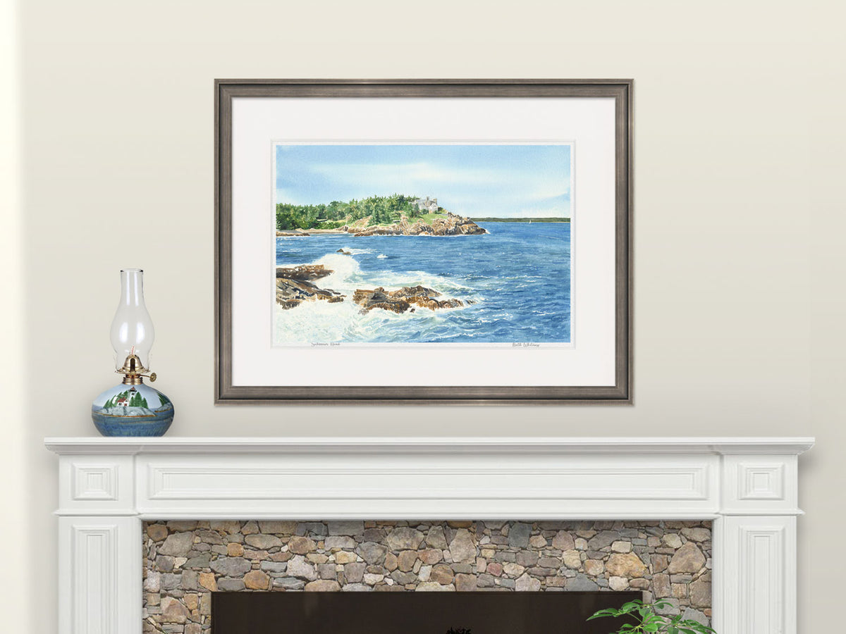 Framed watercolor print of Schooner Head, Acadia, Maine, in a warm wood frame above a fireplace mantel.