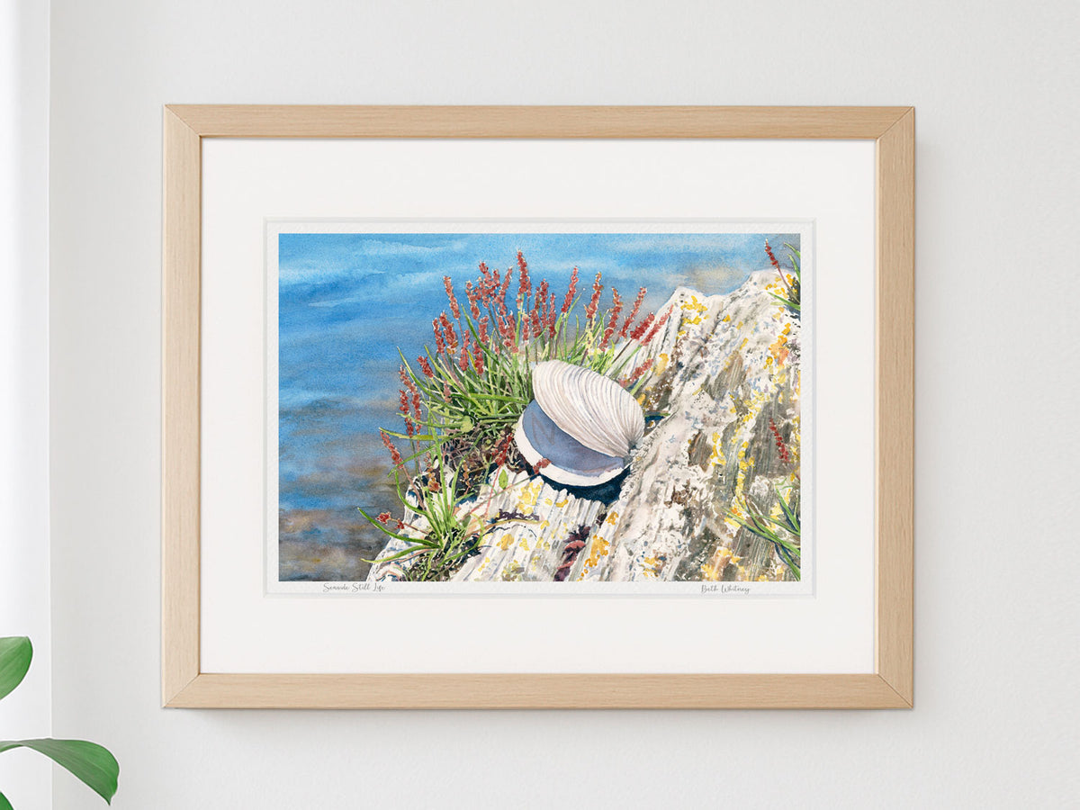 Framed watercolor print of Seaside Still Life, Orr's Island, Harpswell, Maine, in a warm wood frame on a neutral wall.