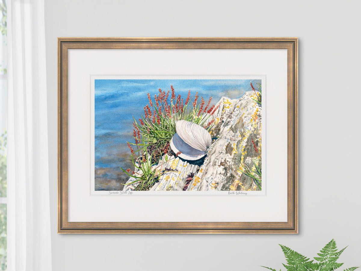 Framed watercolor print of Seaside Still Life, Harpswell, Maine, in a gold frame on a neutral wall.