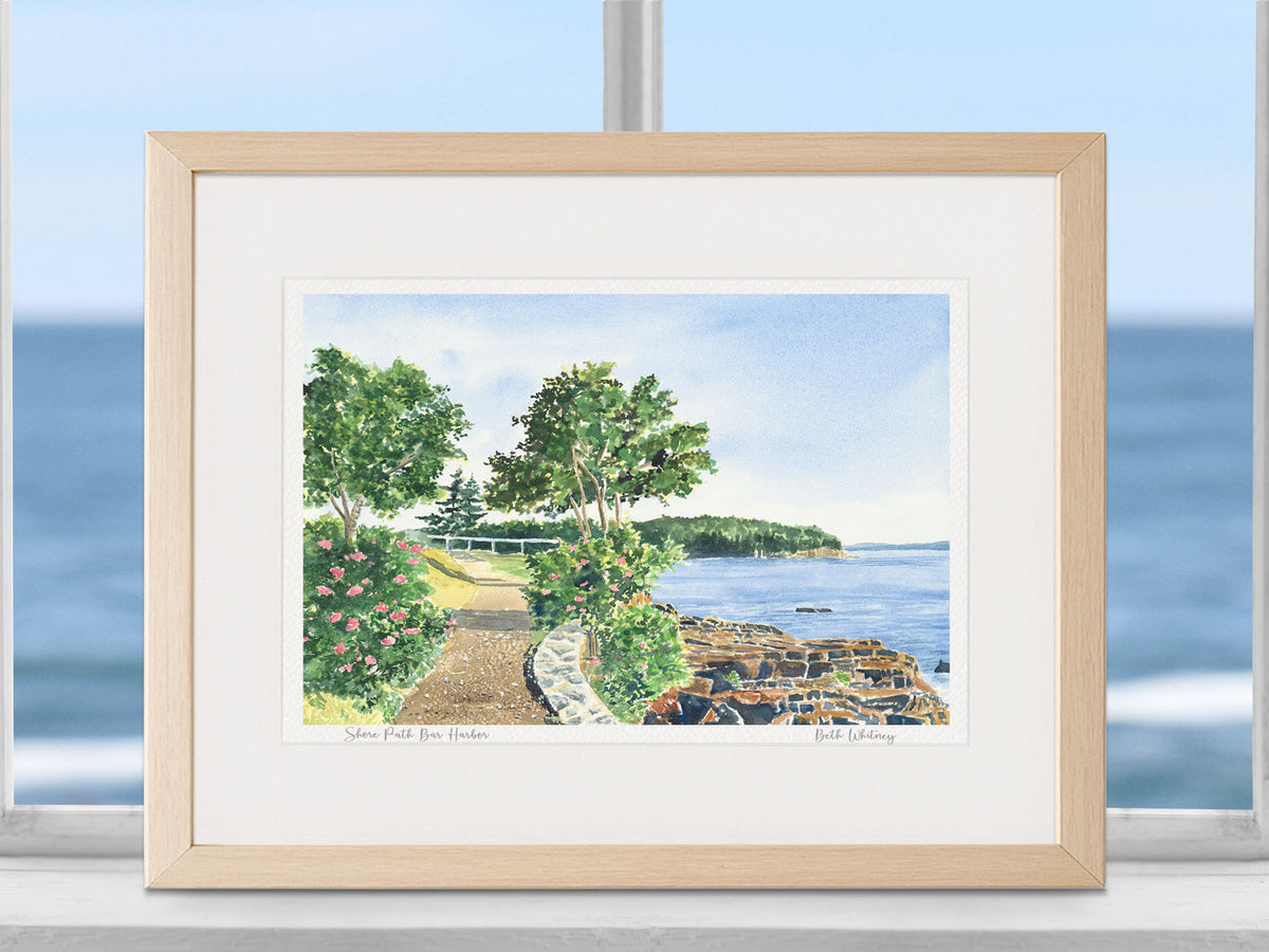 Framed watercolor print of Shore Path Bar Harbor, Acadia, in a warm wood frame in a coastal window decor.
