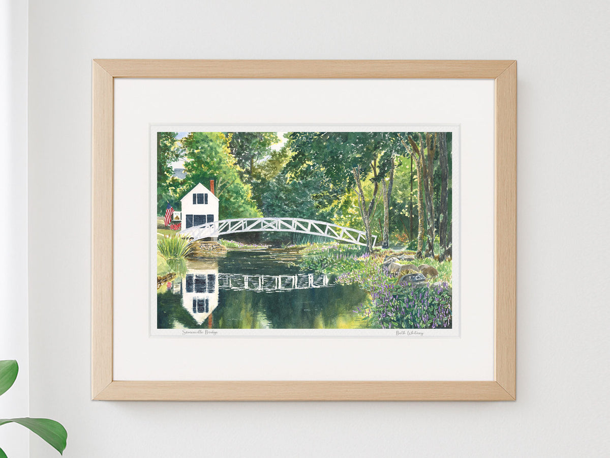 Framed watercolor print of Somesville Bridge, Mount Desert Island, Maine, in a warm wood frame on a neutral wall.