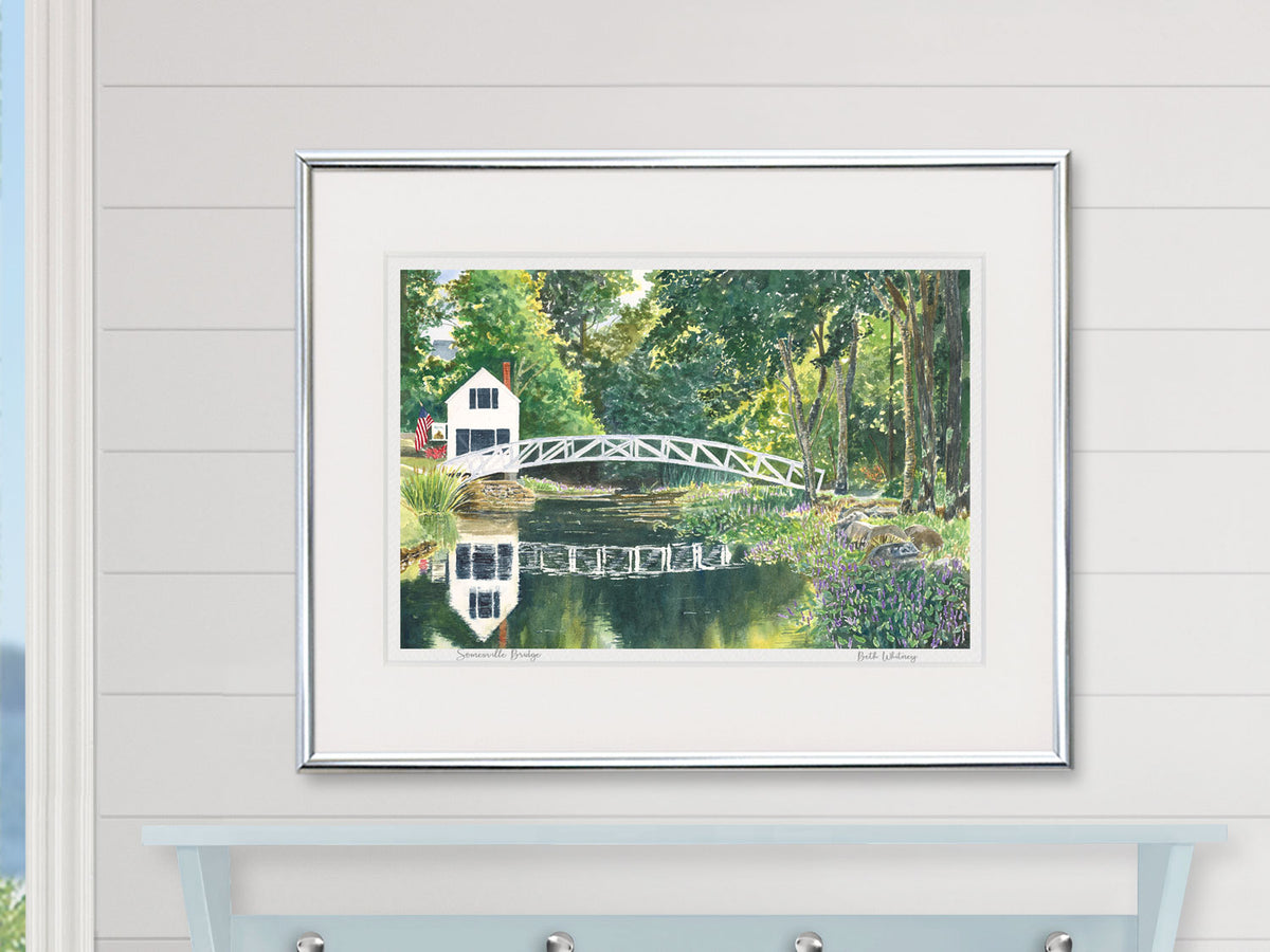 Framed watercolor print of Somesville Bridge, Mount Desert Island, in a silver frame over a nautical blue shelf.