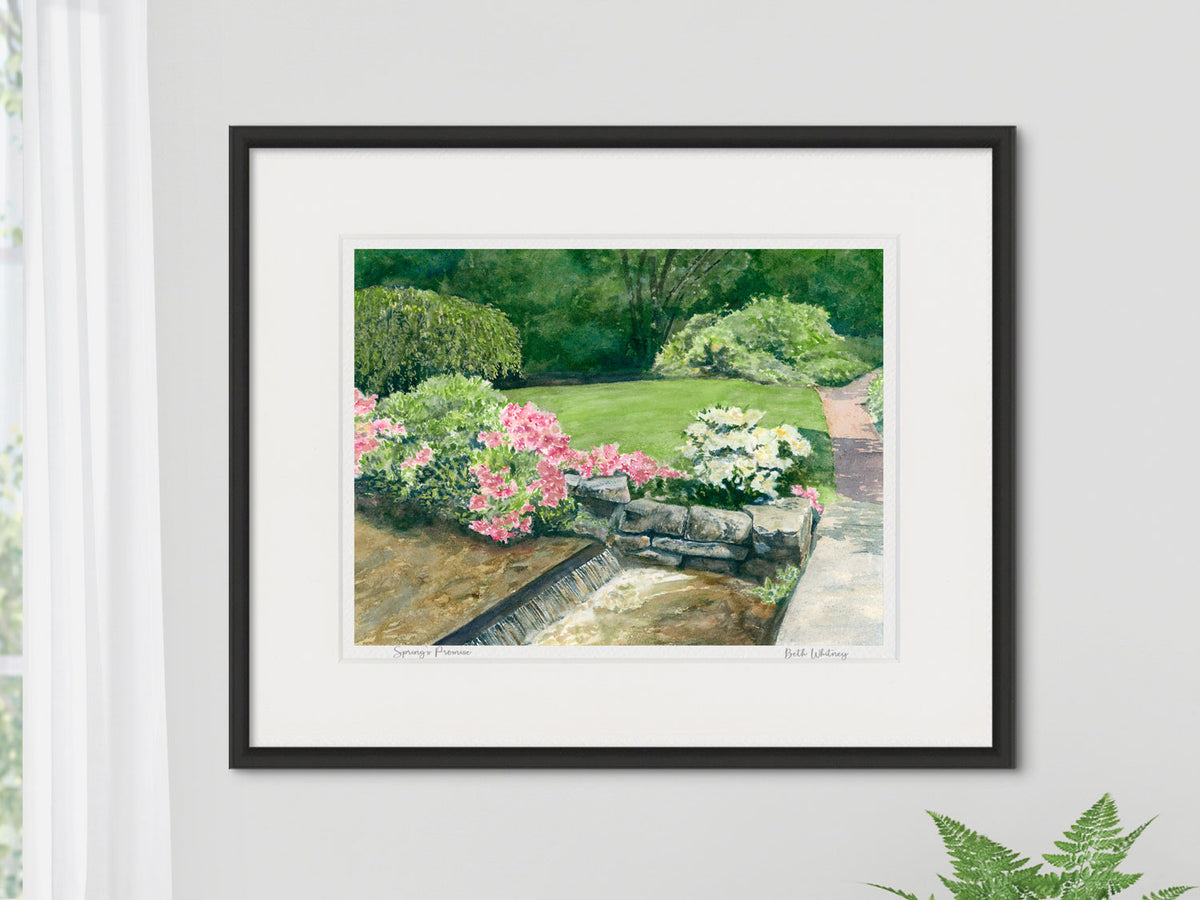 Framed watercolor print of Spring's Promise, Asticou Garden, Maine, in a contemporary black frame beside a window with sheer curtain and houseplant.