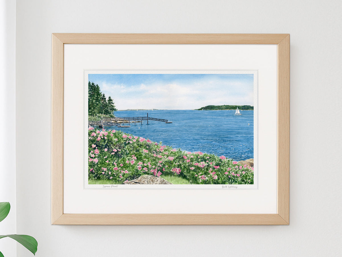 Framed watercolor print of Spruce Point, Boothbay Harbor, Maine, in a warm wood frame on a neutral wall.
