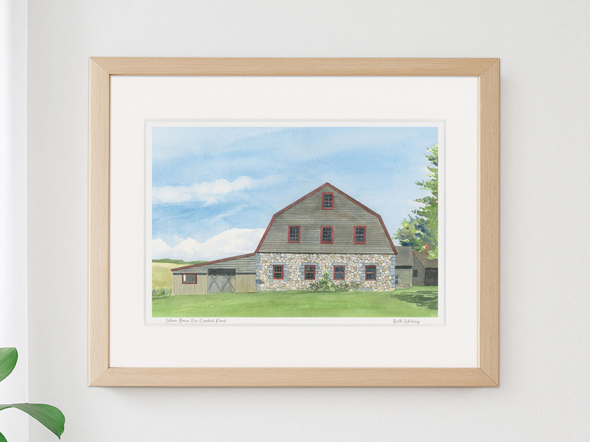Framed watercolor print of Stone Barn on Crooked Road, Salsbury Cove, Maine, in a warm wood frame on a sunny wall.