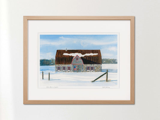 Framed watercolor print of Stone Barn in Winter, Salsbury Cove, Maine, in a warm wood frame on a neutral wall.
