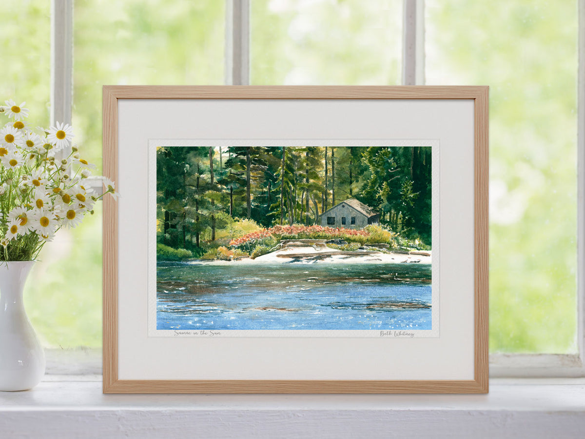 Framed watercolor print of Sumac in the Sun, Boothbay Harbor, Maine, in a natural wood frame on a windowsill beside a vase of flowers.