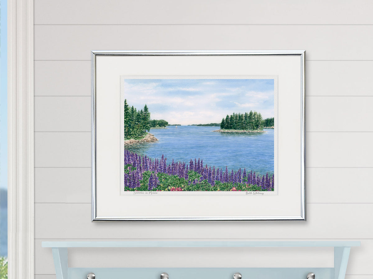 Framed watercolor print of Summer in Maine, Penobscot Bay, Maine, in a silver frame on a coastal inspired shiplap wall.
