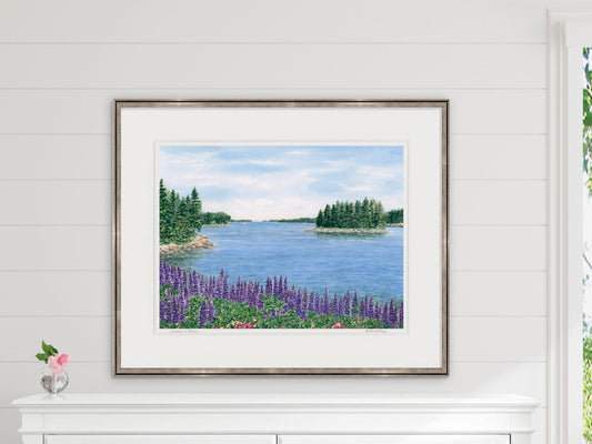 Framed watercolor print of Summer in Maine, Deer Isle, Maine, in a gold frame over over a white dresser and coastal inspired shiplap wall decor.