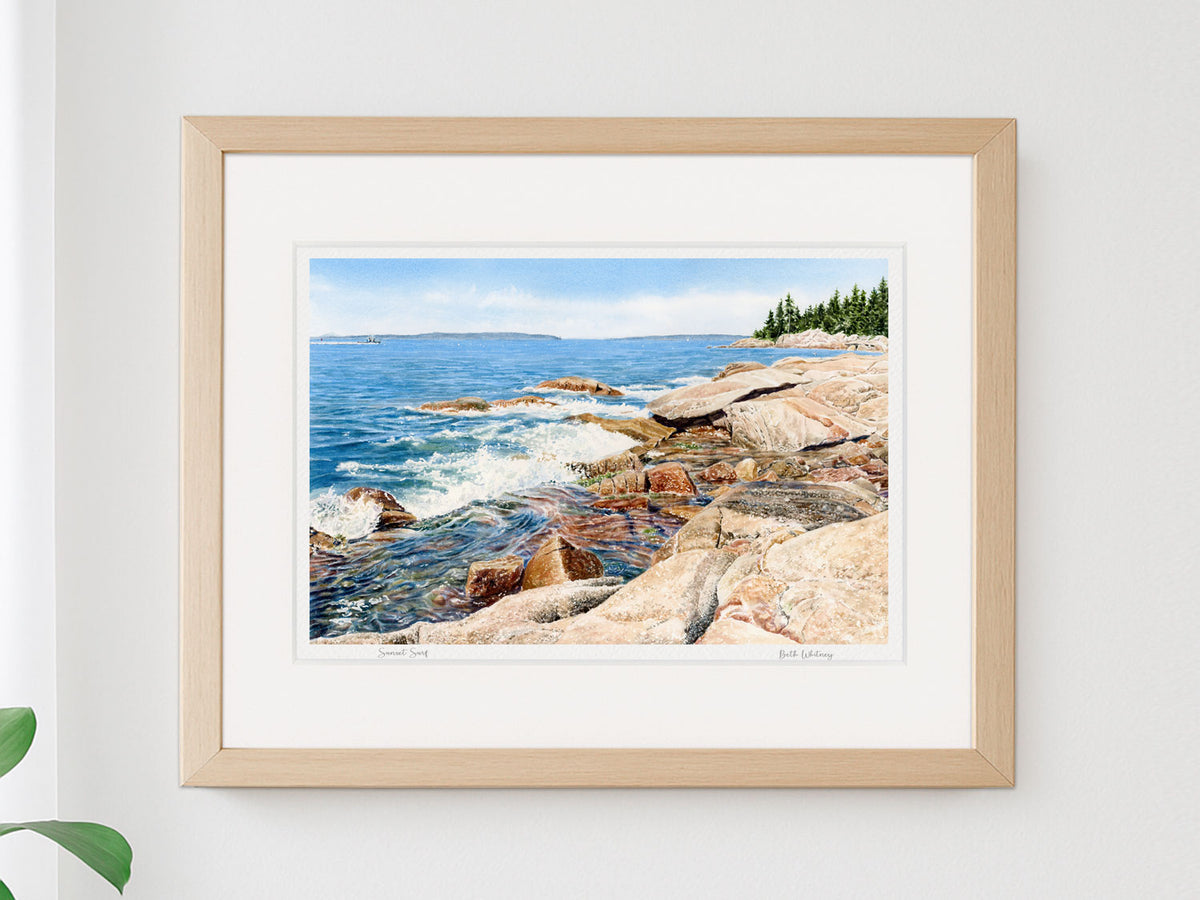 Framed watercolor print of Sunset Surf, Deer Isle, Maine, in a simple wood frame on a brightly lit neutral wall.