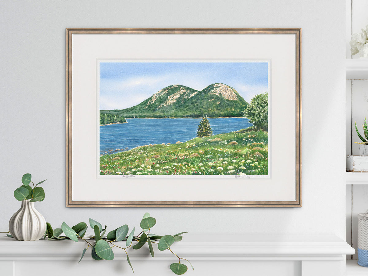 Framed watercolor print of The Bubbles, Jordan Pond, Acadia, in a gold frame in a lifestyle setting.