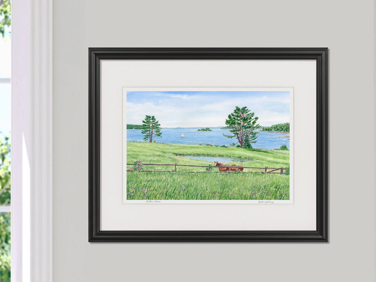 Framed watercolor print of Windswept View, Blue Hill peninsula, Maine, in a black frame beside a sunny window.