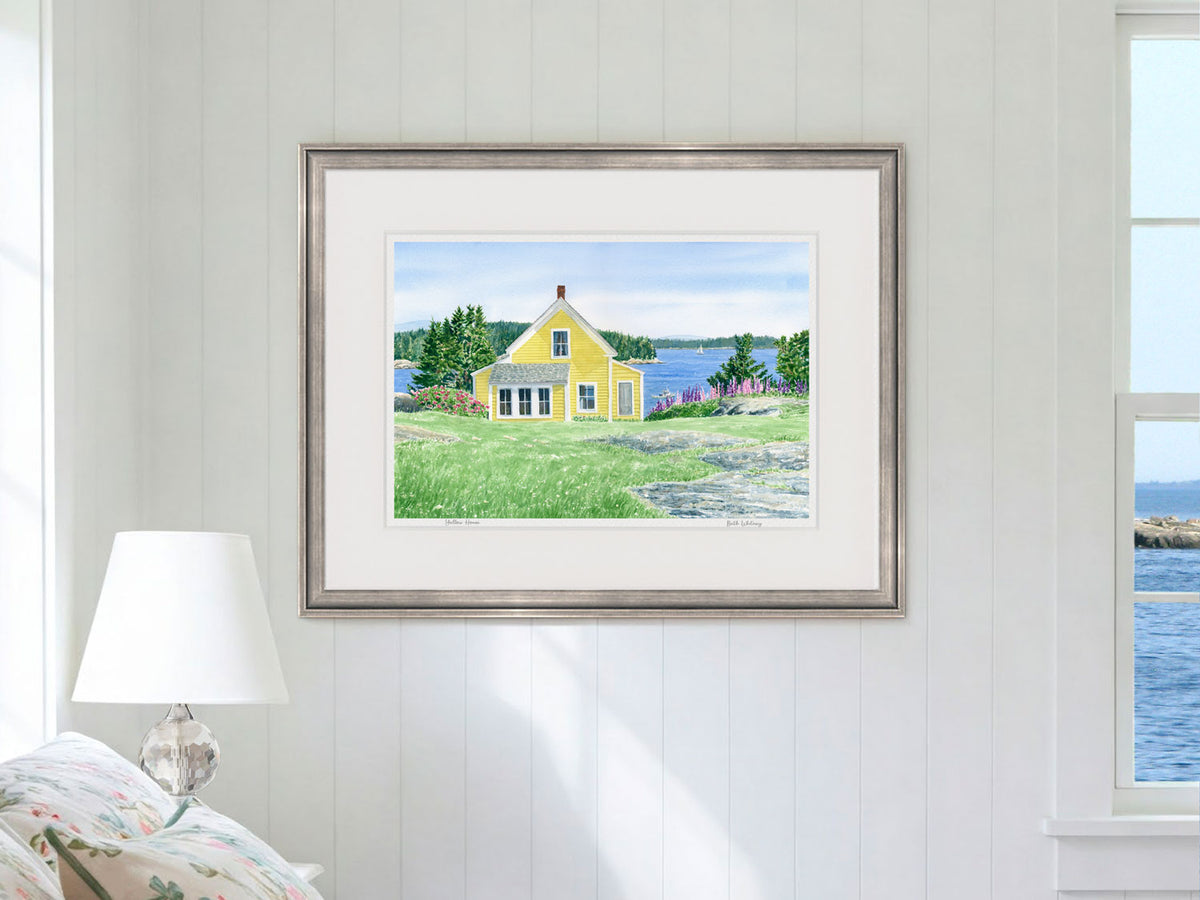 Framed watercolor print of Yellow House, Stonington, Maine, in a pewter frame in a coastal bedroom lifestyle setting.