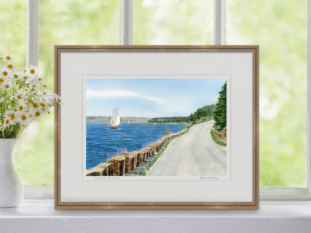 Framed watercolor print of Sailing on the Sound, Somes Sound, Maine, in a warm wood frame in a window setting with flowers.