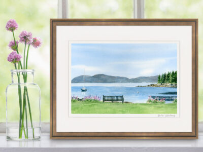 Watercolor painting of a bench overlooking a peaceful ocean with island and Acadia mountains. Shown on a window shelf with flowers.