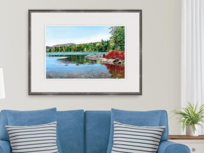 Watercolor of Eagle Lake in Acadia with glassy water and fall foliage. Shown over a loveseat.